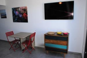 ein Esszimmer mit einem Tisch und Stühlen sowie einem TV in der Unterkunft Appartement avec grande terrasse vue sur mer in Banyuls-sur-Mer