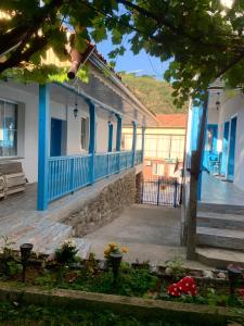 a house with blue trim and a porch with flowers at Цяла Ваканционна Къща- Florina Houses in Goranovtsi