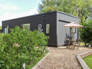 a black tiny house with a table and an umbrella at Kub House in Tring