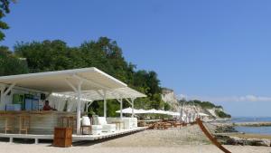 un bar en una playa con sillas y sombrillas en Lighthouse Golf Apart Complex&Villas, en Balchik