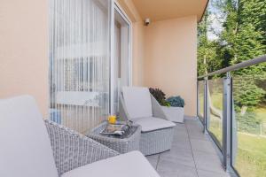 Un balcón con una silla blanca y una mesa. en DreamView Premium Apartment Wisła Kamienna by Renters, en Wisła
