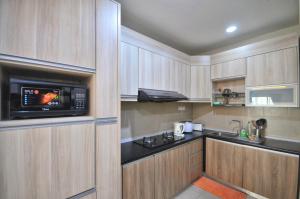 cocina con armarios de madera y microondas en Rusnoor Homestay Alami Residensi 2-17-2, en Shah Alam