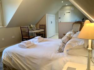 a bedroom with a white bed with towels on it at Fox Inn in Darsham