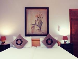 a bedroom with two beds with pillows and a painting at Winelands Villa Guesthouse and Cottages in Somerset West