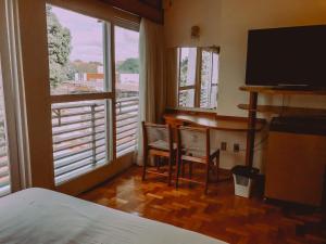 a bedroom with a bed and two chairs and a television at Hotel Cataguases in Cataguases
