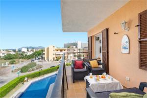 balcone con divano, tavolo e piscina di Tamarels beach apartment in Pollensa a Pollença