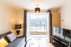 1-bedroom apartment with balcony, Hoddesdon في هوديسدون: غرفة معيشة مع أريكة وتلفزيون