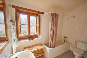 a bathroom with a tub and a toilet and a sink at Masia de Vallforners in Tagamanent