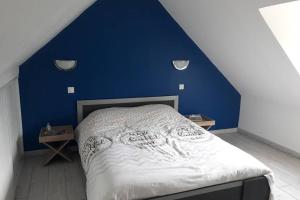 een slaapkamer met een blauwe muur en een bed bij Au Dom-icile in Monceaux-en-Bessin