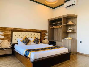 a bedroom with a large bed with a wooden headboard at Gia An Hung Guest House in Mui Ne