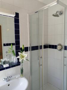 a bathroom with a sink and a shower with a vase of flowers at The Tudor Hotel in Harrow