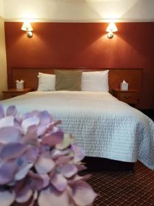 a hotel room with a bed with purple flowers at The Tudor Hotel in Harrow