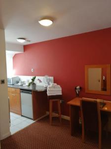 a kitchen with red walls and a table and a counter at The Tudor Hotel in Harrow