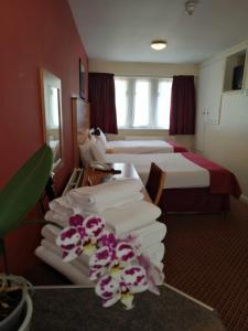 a hotel room with two beds and towels at The Tudor Hotel in Harrow