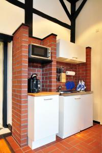 a kitchen with white cabinets and a brick wall at Suite „Herrenhausen“ - stilvolles Apartment in Fachwerkhaus in Hannover