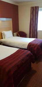 a hotel room with two beds and a window at The Tudor Hotel in Harrow