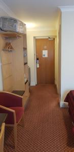 a hallway in a hotel room with a door and a chair at The Tudor Hotel in Harrow