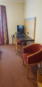 a room with a desk, chairs and a laptop computer at The Tudor Hotel in Harrow