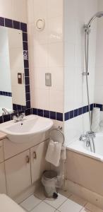 a bathroom with a sink and a toilet and a tub at The Tudor Hotel in Harrow