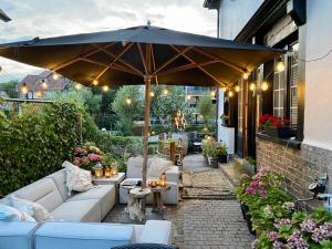 a patio with couches and an umbrella at Hotel Villa Verdi in Knokke-Heist