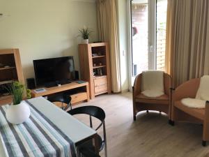 ein Wohnzimmer mit einem Tisch, Stühlen und einem TV in der Unterkunft Fietje 206 - Hohen Wieschendorf in Hohen Wieschendorf