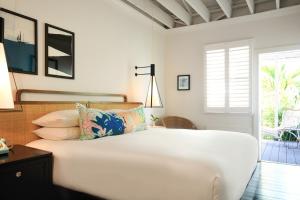 een witte slaapkamer met een bed en een patio bij Ella's Cottages - Key West Historic Inns in Key West