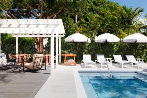 un patio con sillas, piscina y sombrillas en Ella's Cottages - Key West Historic Inns en Cayo Hueso