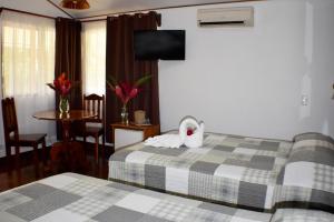 a hotel room with two beds and a swan towel at Hotel Arenal Country Inn in Fortuna