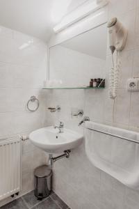 W białej łazience znajduje się umywalka i lustro. w obiekcie Hotel U Valdické brány w Jiczynie