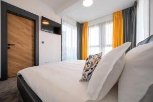 a bedroom with a large white bed and windows at Calvin in Oradea