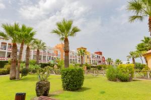 un parque con palmeras y edificios al fondo en Flamingo Golf B, en Sanlúcar de Barrameda