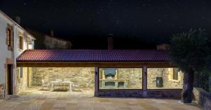 une maison en pierre avec une terrasse la nuit dans l'établissement La Casa De Los Pedros, à Villar