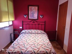 een slaapkamer met een bed met een rode muur bij PENSION LA PARADA in Fabero