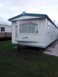 una casa pequeña está estacionada en un patio en L&g FAMILY HOLIDAYS 8 BERTH SEALANDS FAMILYS ONLY AND THE LEAD PERSON MUST BE OVER 30 en Ingoldmells