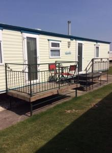 a mobile home with two chairs on a deck at L&g FAMILY HOLIDAYS 8 BERTH SEALANDS FAMILYS ONLY AND THE LEAD PERSON MUST BE OVER 30 in Ingoldmells