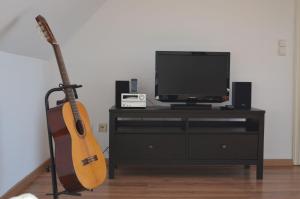 eine Gitarre auf einem Stand neben einem Fernseher in der Unterkunft Ferienwohnung Seefrieden in Westensee