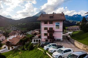 a pink house with cars parked in front of it at Garni Miravalle in Moena