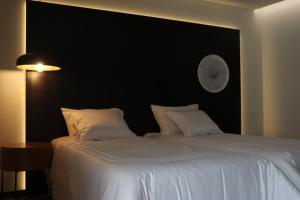a bedroom with a large white bed with a black headboard at ICH Inveja Country House in Paços de Ferreira