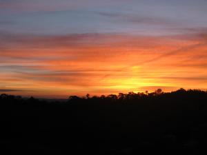a sunset in the sky with trees in the foreground at Poente Guest House in Conceição da Ibitipoca