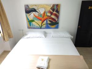 a bed in a room with a painting on the wall at Hotel Tayromar in Santa Marta