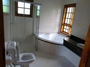 ein Badezimmer mit einer Badewanne, einem WC und einem Waschbecken in der Unterkunft Chalé D'avilas in Monte Verde