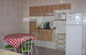 a kitchen with a table and a white refrigerator at Casa do Carlos, praia da Enseada Ubatuba-SP in Ubatuba