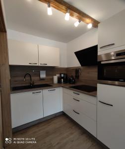 una cucina con armadi bianchi, lavandino e piano cottura di Berghof Apartment Bergwiese Top 31 a Ellmau
