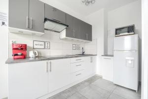 a white kitchen with white cabinets and a refrigerator at Top Oder Apartments- private parking in Szczecin