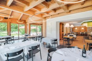 a restaurant with white tables and chairs and wooden ceilings at La Clé Des Champs in Montmélian