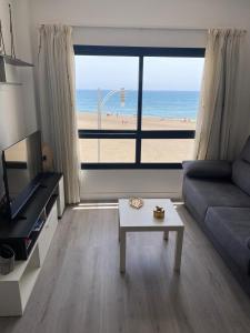 - un salon avec un canapé et une vue sur la plage dans l'établissement Apartamentos Candelarita, à Gran Tarajal