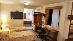 a hotel room with two beds and a desk and a television at Hotel Metrópolis in Sao Jose do Rio Preto