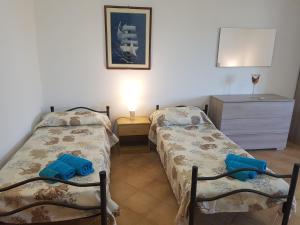 a bedroom with two beds and a dresser with a lamp at Residence Argentiera in Miniera dellʼArgentiera