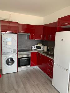 a kitchen with red cabinets and a washing machine at Apartamentos Candelarita in Gran Tarajal