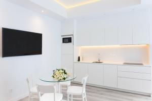 a white kitchen with a glass table and white chairs at Lauser City Suites in Los Llanos de Aridane